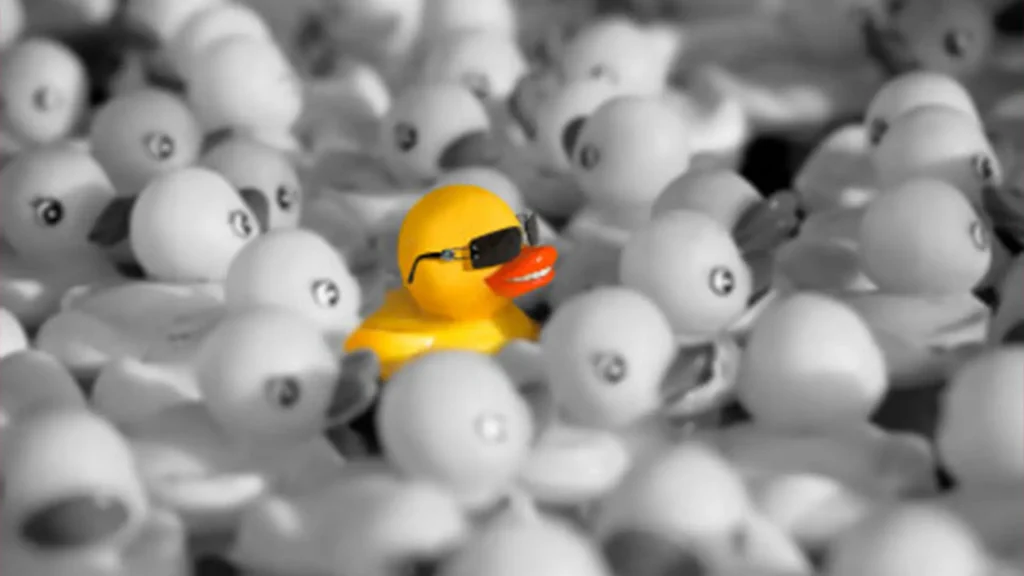 Rubber ducky with glasses surrounded by ordinary rubber duckies
