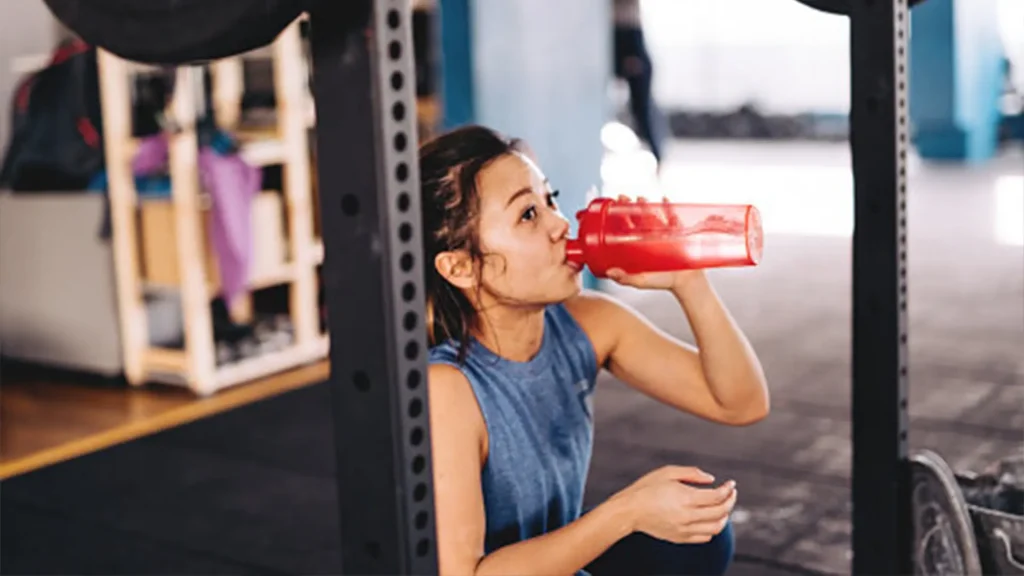 Woman drinking water in a gym