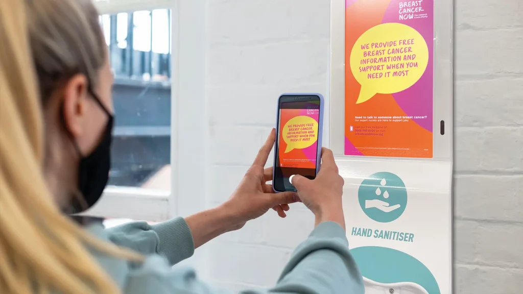Woman taking a photo of a digital screen in a waiting room
