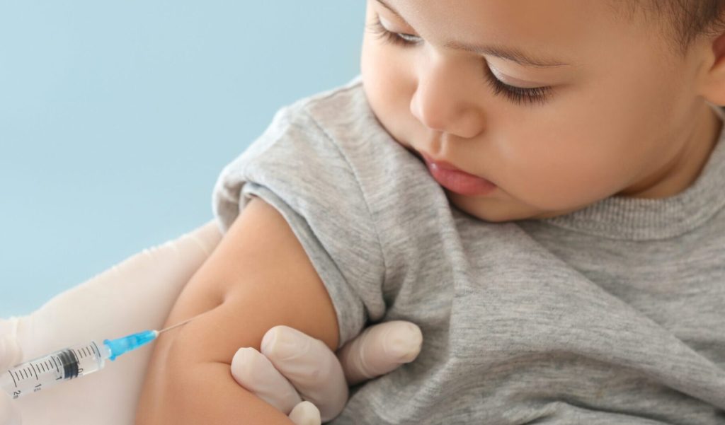 A young toddler is getting a vaccine injection.