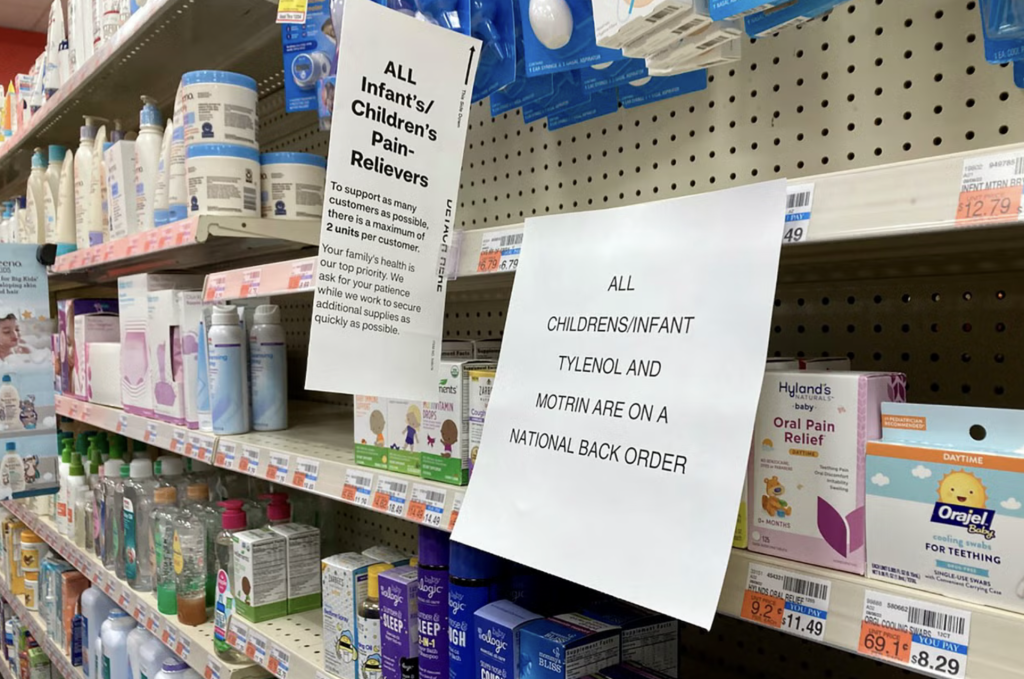 An empty pharmacy shelf with a printed sign affixed that says All childrens/infant tylenol and motrin are on a national back order.