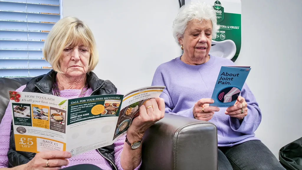 Elder people reading leaflets in a GP waiting room